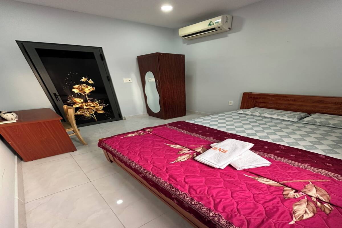 Quarto com uma cama, mesa de cabeceira de madeira, guarda-roupa e ar condicionado.