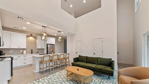 A modern kitchen with white cabinets, a central island with bar stools, and pendant lighting.