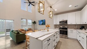 A modern kitchen with white cabinets, a large island, and stainless steel appliances.