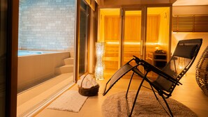 A spa area with a hot tub, a wicker basket, a black chair, and a textured rug. - ReVIERA Resort Villa (Chatan)