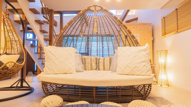 A cozy, circular seating area with a woven canopy, a cushioned bench, and a wicker chair. - ReVIERA Resort Villa (Chatan)