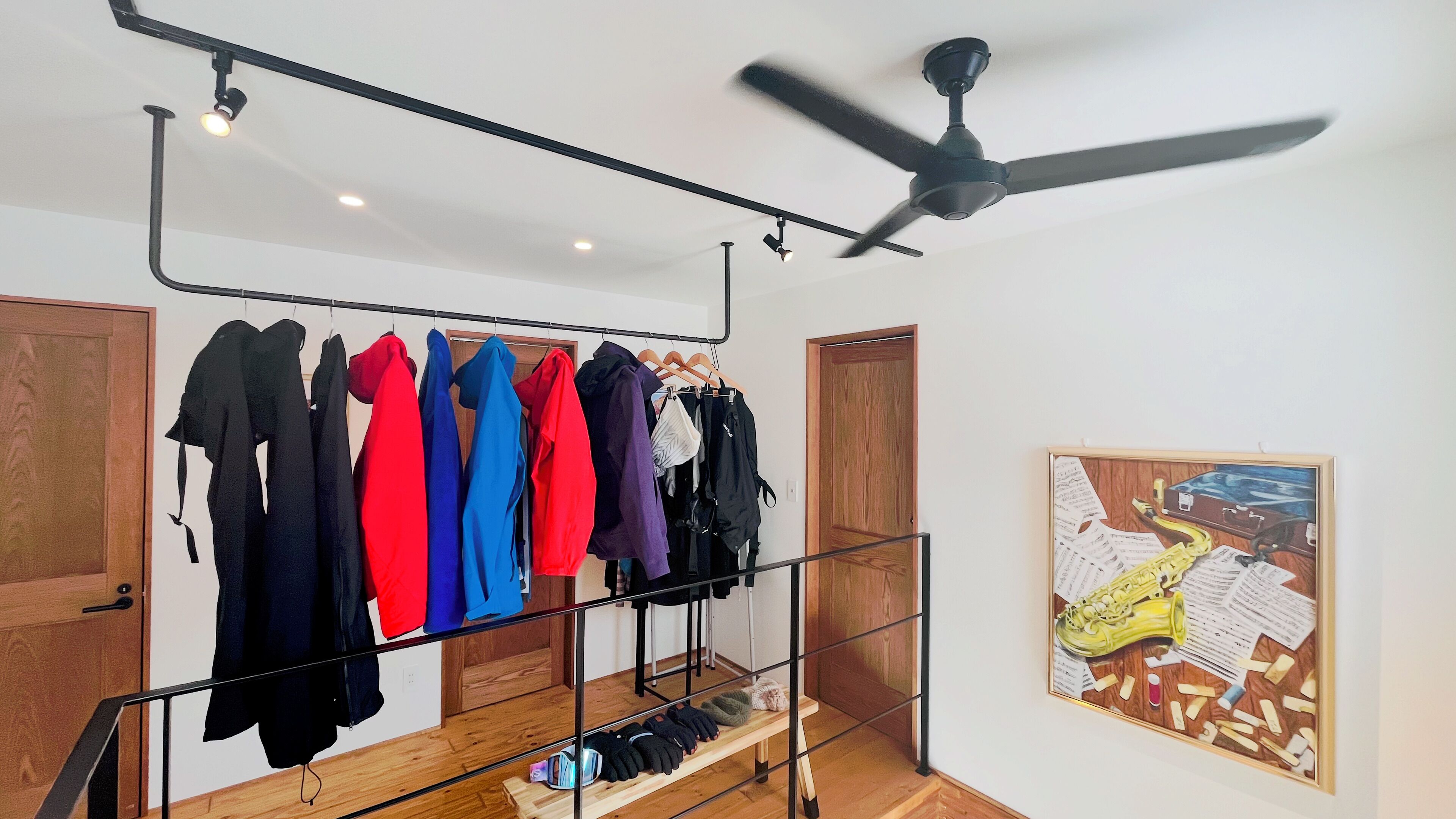 A room with a clothing rack, a ceiling fan, and a framed artwork on the wall.