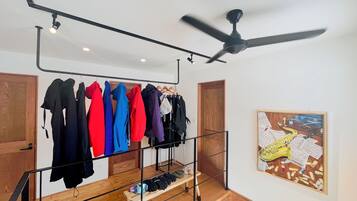 A room with a clothing rack, a ceiling fan, and a framed artwork on the wall.