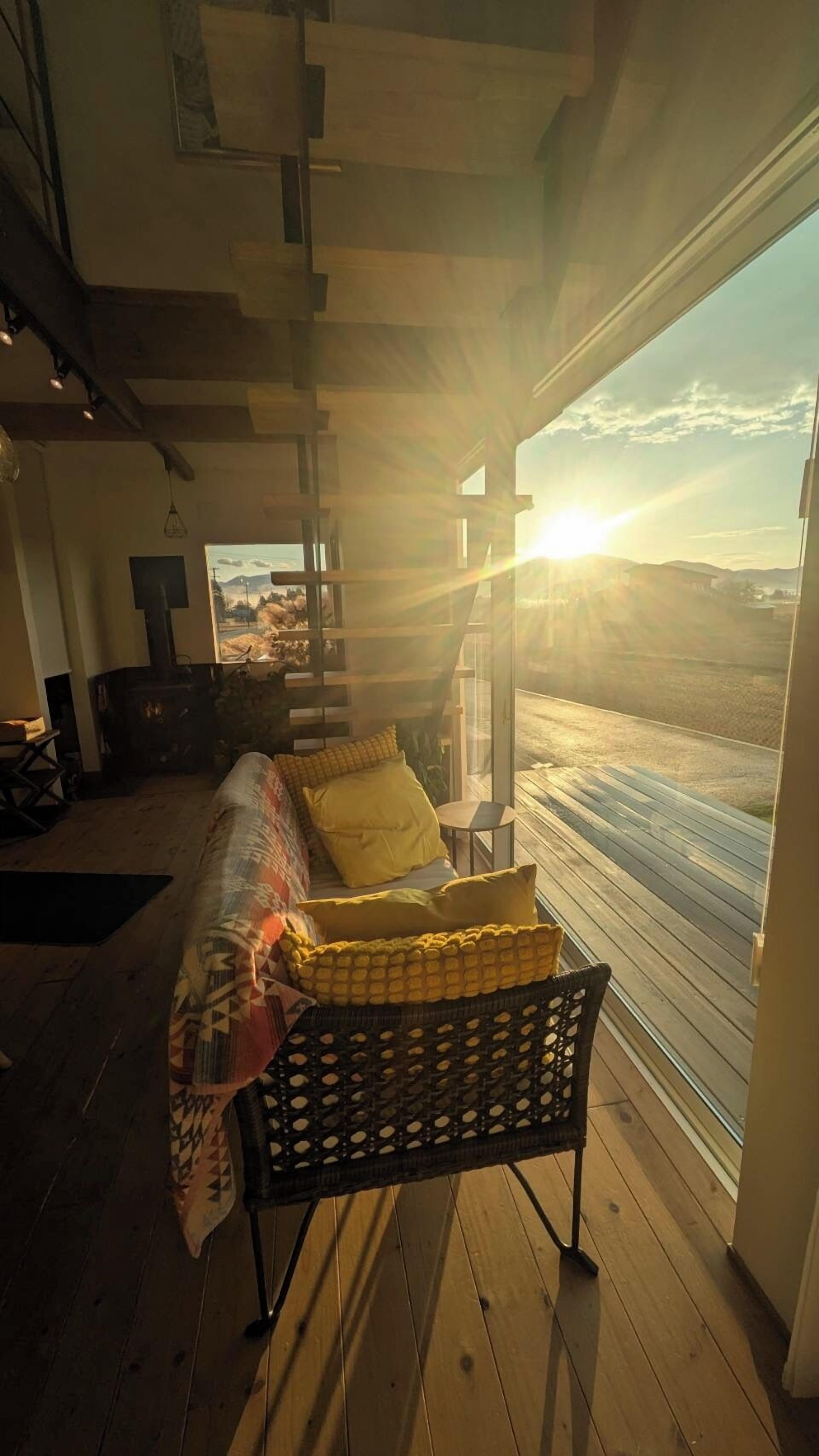 A cozy room with a bed, a window with a view of a landscape, and a wooden floor.