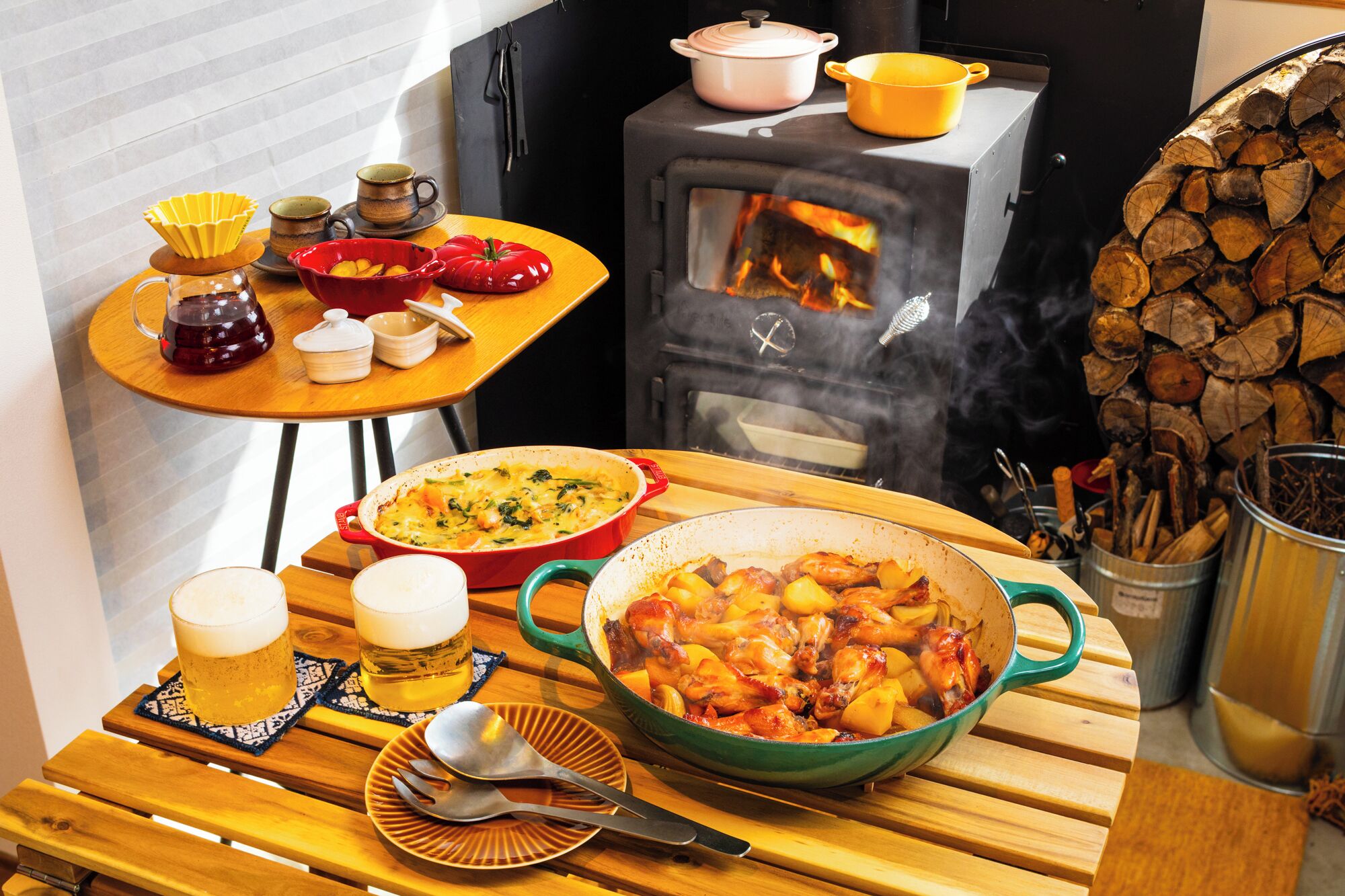 A rustic kitchen with a wood stove, cooking pots, and a dining table set for a meal.