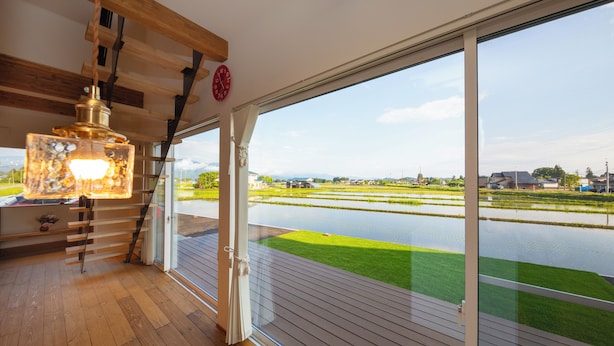 Un interior moderno con un gran ventanal que da a una vista de un cuerpo de agua y campos verdes.