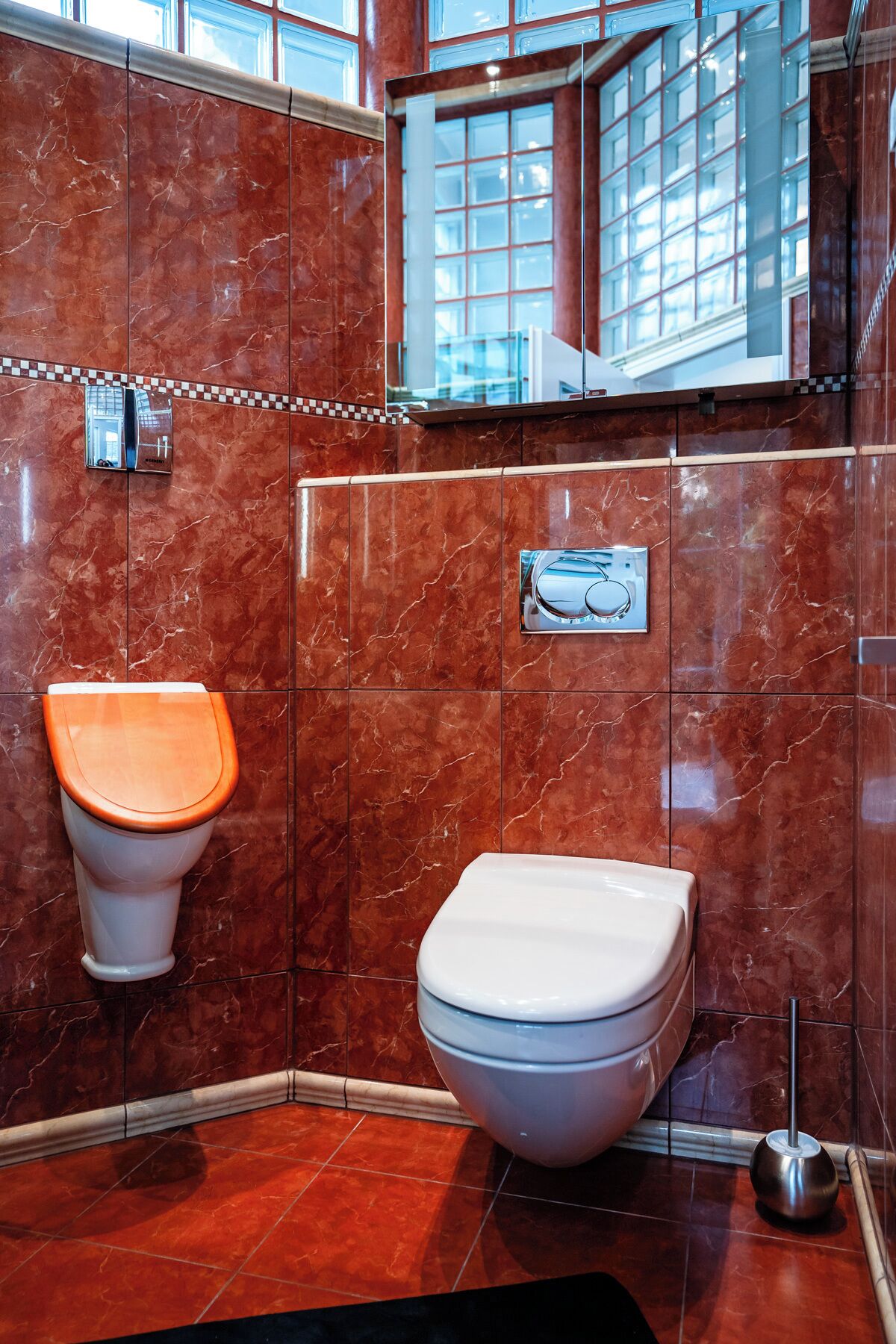 A modern bathroom with a marble wall, a toilet, and a bidet.