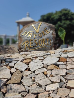 Un letrero de piedra con el texto 'NATURE RESORTS' en letras doradas.
