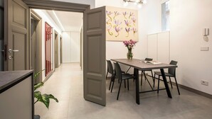 A modern dining area with a table and chairs, a vase of flowers, and a painting on the wall. - Contemporary Elegance: New 3-bedroom loft between Trastevere and the Vatican (Roma)