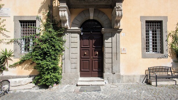 A building with a central entrance featuring a double door, flanked by two windows with barred glass. - Contemporary Elegance: New 3-bedroom loft between Trastevere and the Vatican (Roma)