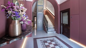 A hallway with a marble staircase, a reception desk, and a large vase of flowers. - Contemporary Elegance: New 3-bedroom loft between Trastevere and the Vatican (Roma)