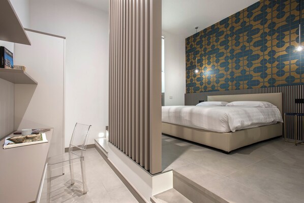 Une chambre moderne avec un grand lit, une table de chevet et un mur orné d’un motif géométrique.