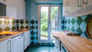 A compact kitchen with a dishwasher, a sink, and a window leading to a garden.