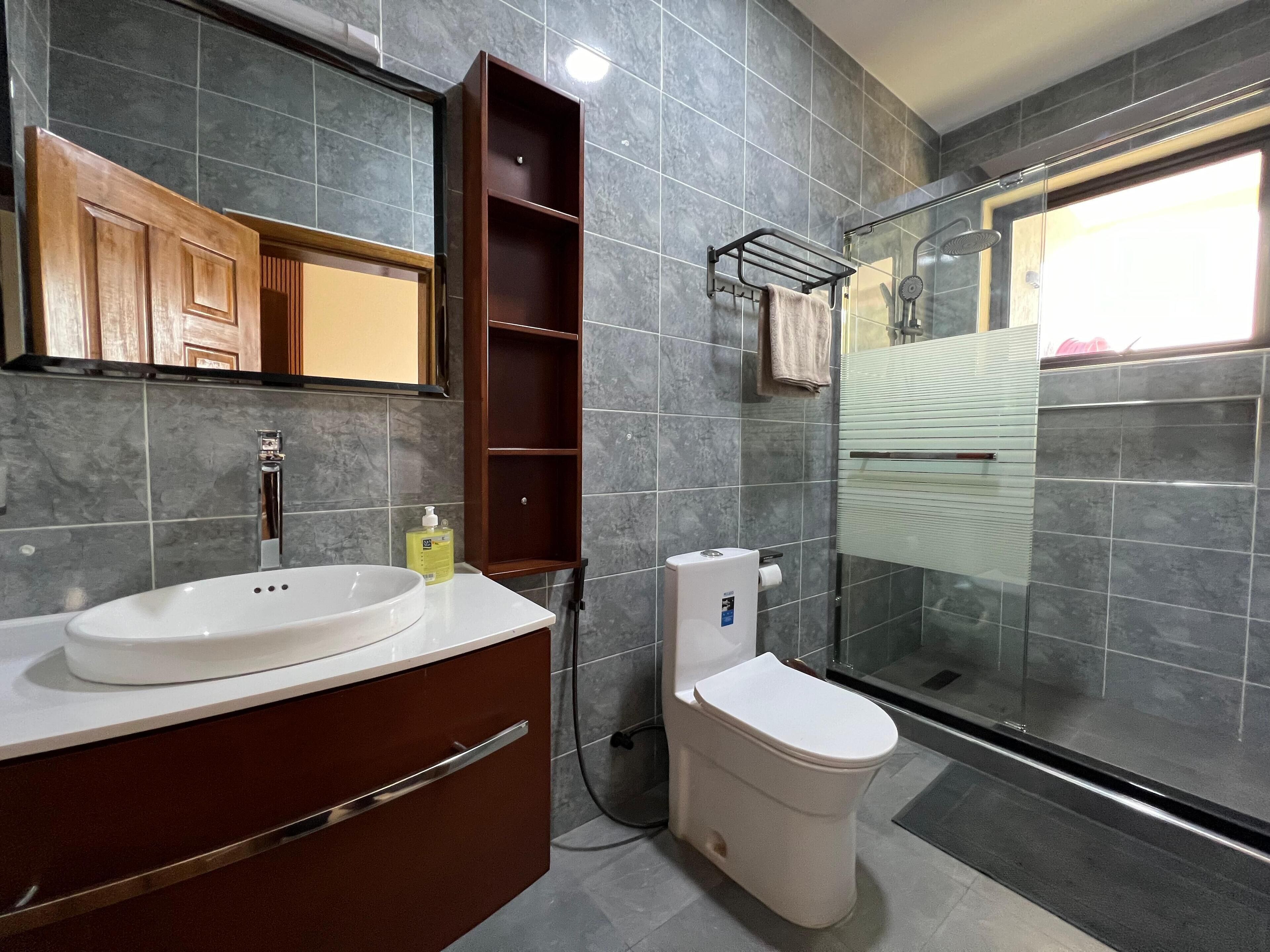 A modern bathroom with a large mirror, a sink, a toilet, and a shower area.