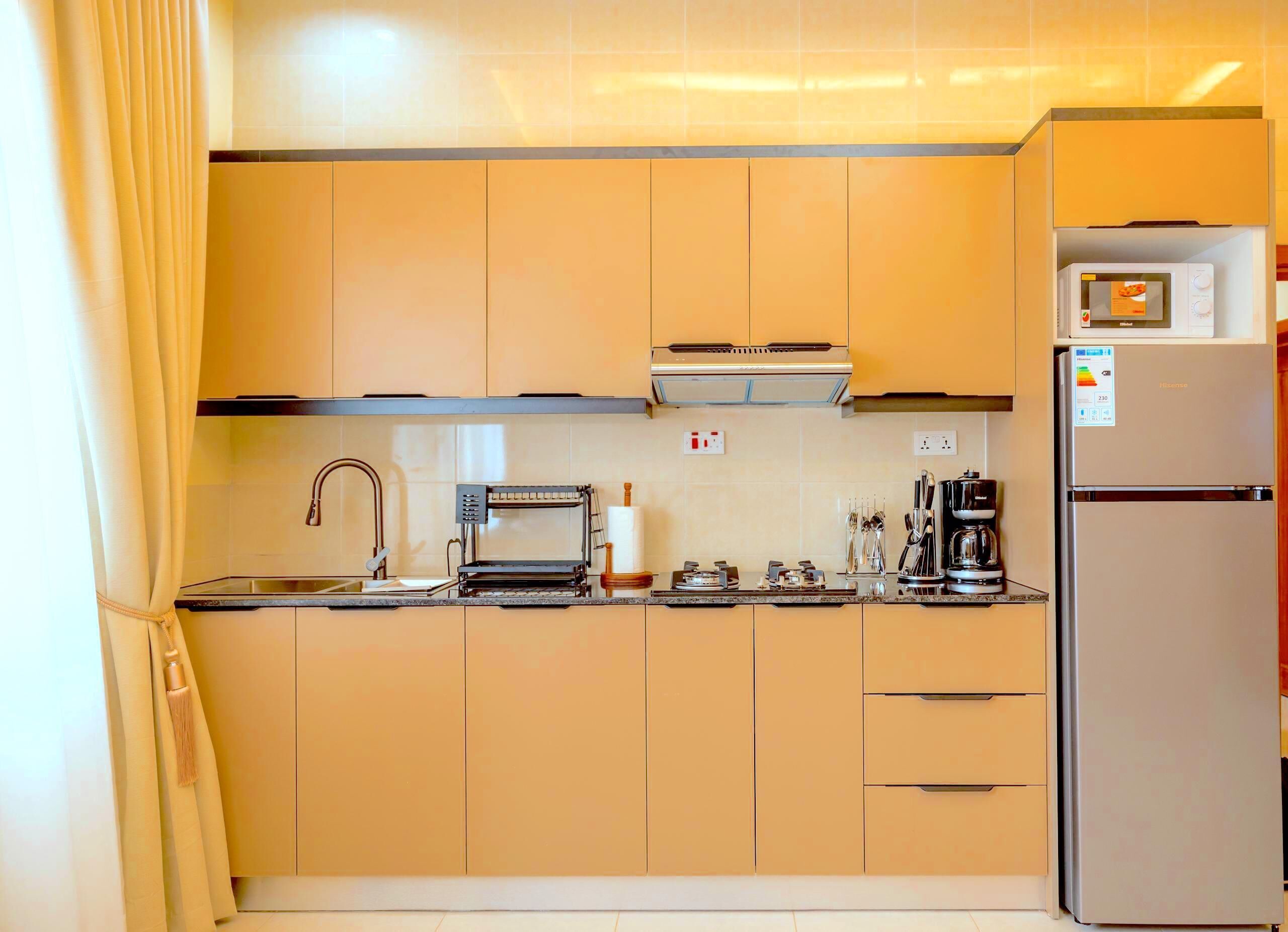 Una cucina compatta con forno a microonde integrato, macchina del caffè e tostapane.