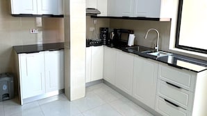 Una cocina moderna con gabinetes blancos, encimeras negras y electrodomésticos de acero inoxidable.
