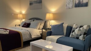 Un dormitorio con cama, mesitas de noche, un sofá, una mesa de centro y una alfombra.