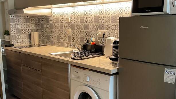 Cocina compacta con lavadora y secadora integradas, microondas y lavaplatos.