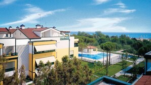 A modern hotel with a pool, surrounded by greenery and a clear view of the sea.