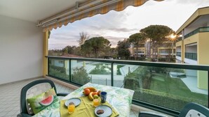 A balcony with a table set for breakfast, overlooking a building and trees.