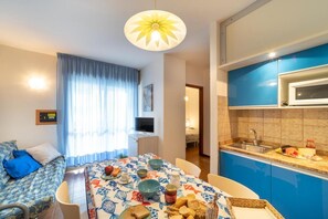 Un espace de vie compact comprenant un coin repas, une kitchenette et un lit.