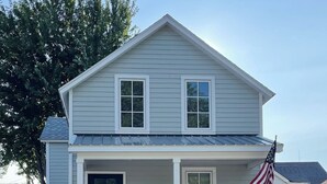 A two-story house with a front porch, a black front door, and an American flag. - Remodeled Downtown Cottage, close to St Clair River, McMorran, Convention Center (Port Huron)