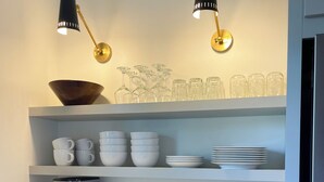 A kitchen with white cabinets, a coffee maker, and shelves holding bowls, cups, and glasses. - Remodeled Downtown Cottage, close to St Clair River, McMorran, Convention Center (Port Huron)