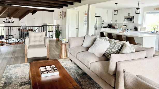 Amplia sala de estar con un sofá grande, una mesa de centro y vista a la cocina.