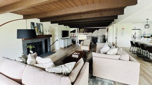 Amplia sala de estar con chimenea, muebles modernos y una cocina al fondo.