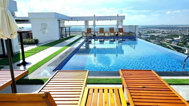 Piscina infinita en la azotea con tumbonas de madera, vista de la ciudad y un cartel que dice 'Today is a good day'.