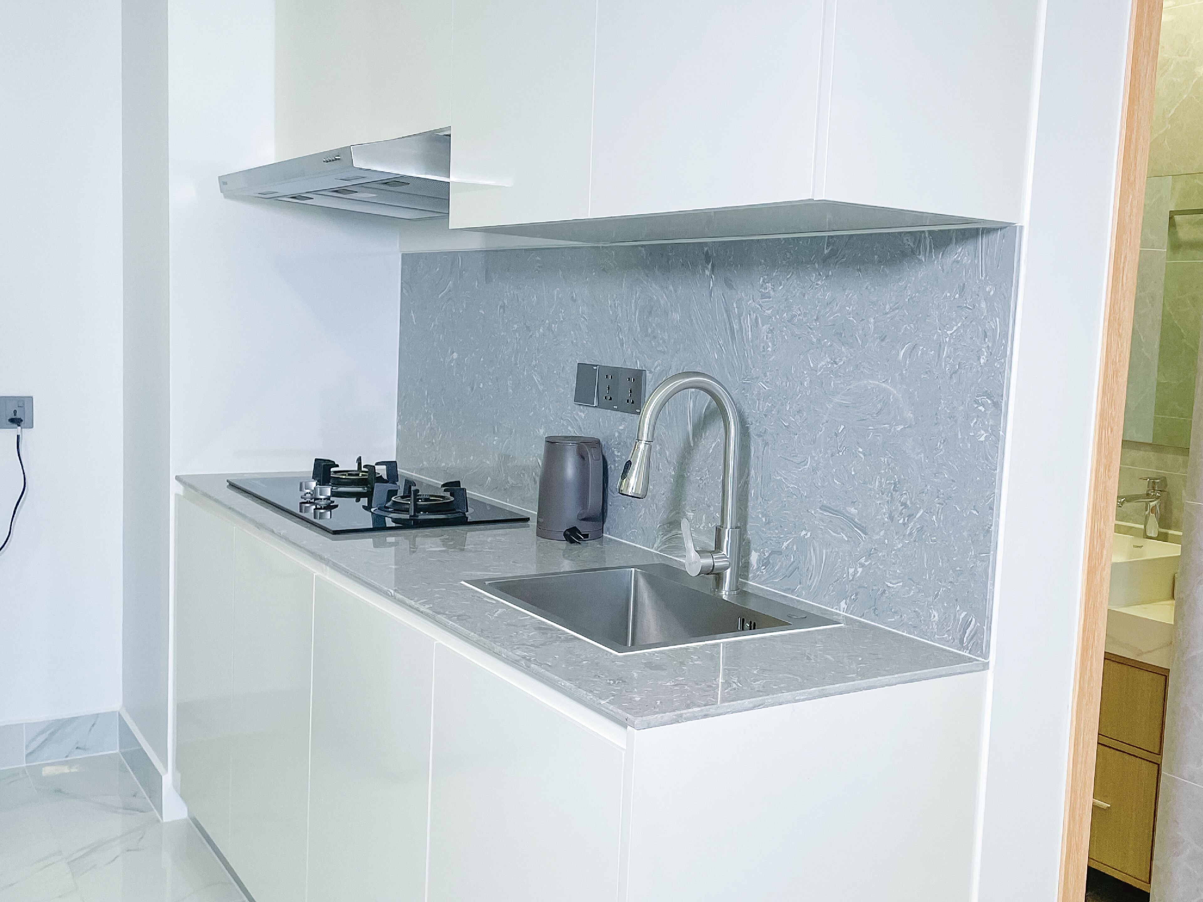 A modern kitchen with a stainless steel sink, a gas stove, and a kettle.