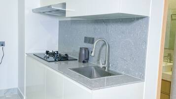 A modern kitchen with a stainless steel sink, a gas stove, and a kettle.