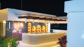 Un moderno vestíbulo de hotel con una mesa de recepción, ventanas arqueadas y vistas nocturnas de la ciudad.