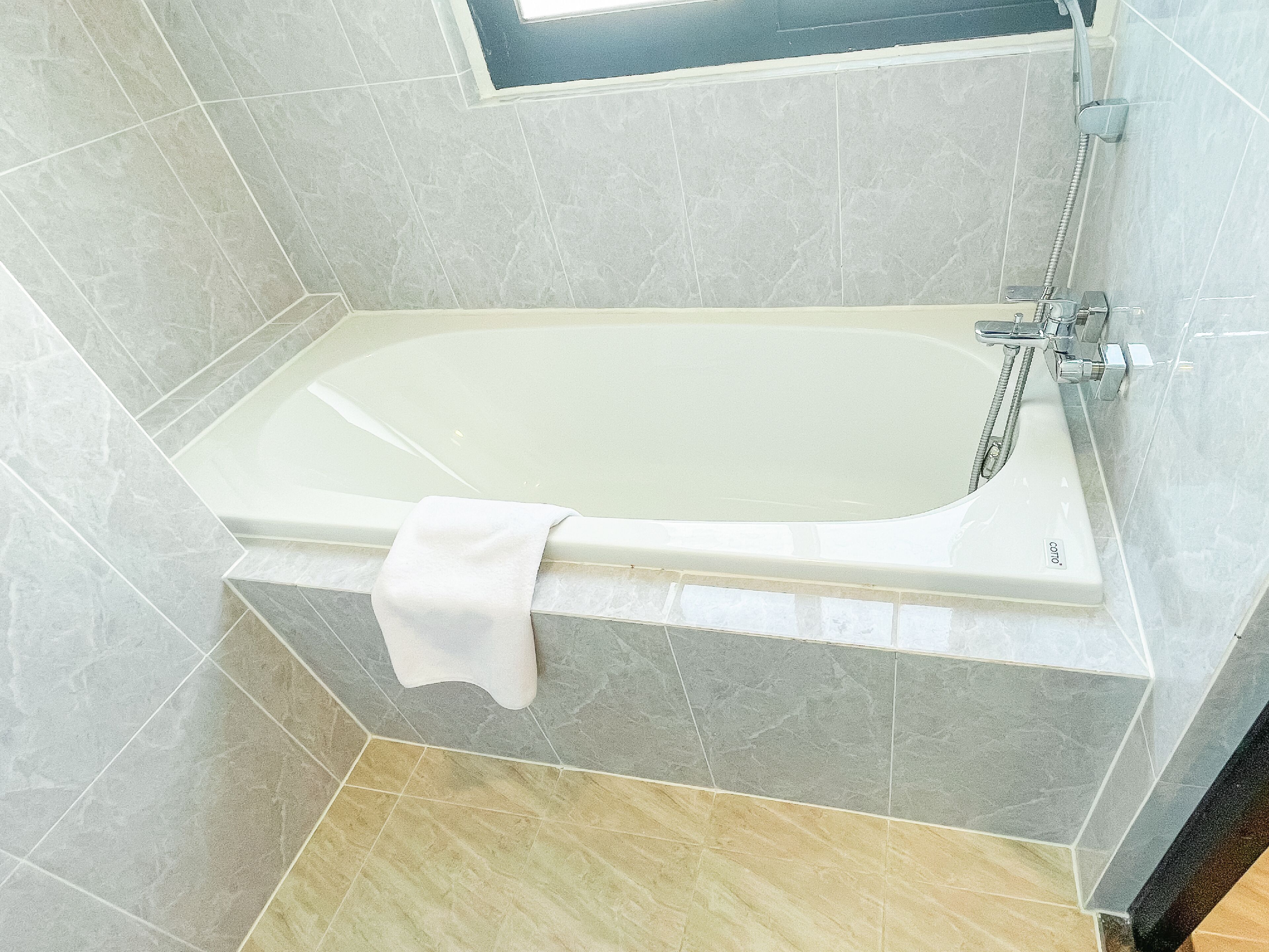 A modern bathroom with a bathtub, a shower, and a window.