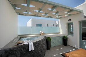 A rooftop terrace with a stone jacuzzi, a sunshade, and a potted plant. - Katerina Villas 11 12 13 & 3PriveJacuzzi (Santorini)