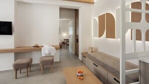 A modern kitchen with a wooden countertop, two stools, a table with fruit, and a view into the dining area. - Katerina Villas 11 12 13 & 3PriveJacuzzi (Santorini)