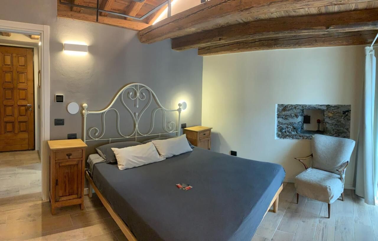 Une chambre avec un grand lit, des tables de chevet en bois, une chaise, un mur en pierre décoratif et un plafond en bois.