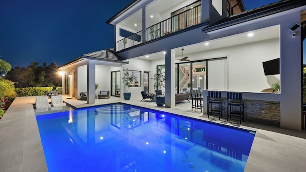 Ein modernes, zweistöckiges Haus mit Swimmingpool, Außenbereich und Balkon.