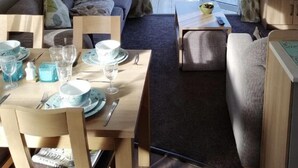 Et hyggeligt spiseområde med et træbord dækket til to personer, inklusiv tallerkener, glas og bestik.