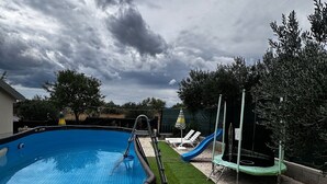 A swimming pool with a slide, surrounded by artificial grass and trees. - kuća za odmor ante (selo)