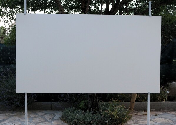 A blank billboard in an outdoor setting with stone pavement and greenery. - kuća za odmor ante (selo)
