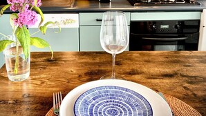 Una cocina moderna con una mesa de madera preparada para una comida, un jarrón de flores y una tetera sobre la estufa.