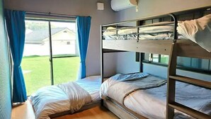 A bunk room with two beds, a window with blue curtains, and an air conditioning unit on the wall. - Shima-shi kodate (Shima)