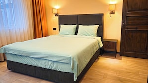 A neatly made bed with a light-colored duvet, a dark headboard, and two bedside lamps. - GARDEN'S ROOM (Edirne)