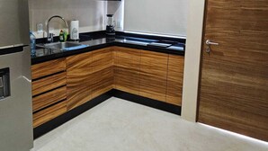 A modern kitchen with wooden cabinets, a stainless steel refrigerator, and a black countertop. - Elegant 1 Bedroom - 1 bathroom Apartment (Tulum)