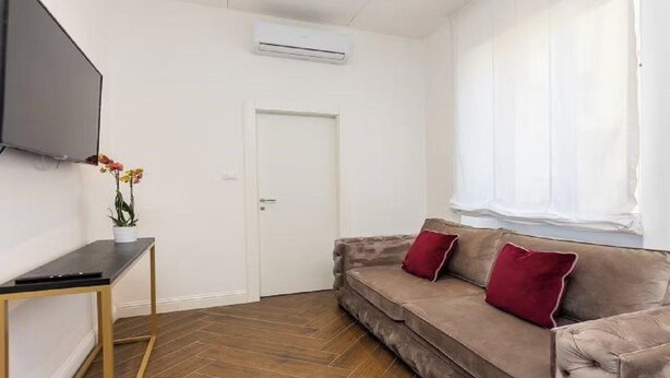 A living room with a brown sofa, a small table, and a flat-screen TV.