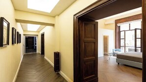 A hallway with wooden flooring, a radiator, and a bed in the adjacent room. - Chic Roman Retreat: Minimalist Luxury in the Heart of Historic Rome (Roma)