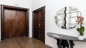 A hallway with wooden doors and a wall-mounted mirror. - Chic Roman Retreat: Minimalist Luxury in the Heart of Historic Rome (Roma)
