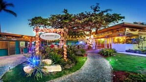 Un espacio al aire libre bien iluminado con un letrero que dice "la pesicadera", rodeado de plantas y un sendero.