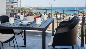 Un balcone con un tavolo apparecchiato per due, vista su una spiaggia e sullo skyline della città.